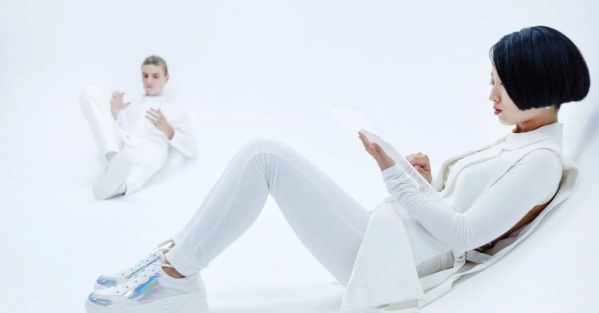 Imagen minimalista de una mujer asiática y un hombre caucásico con ropa blanca sobre un fondo brillante.